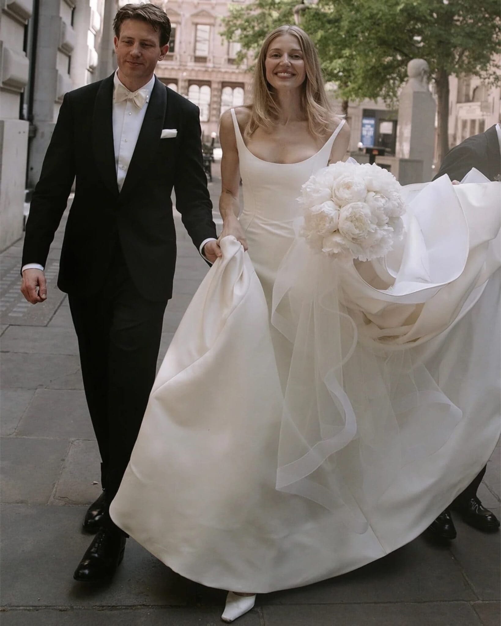 Bride and groom walking outside with wedding bouquet