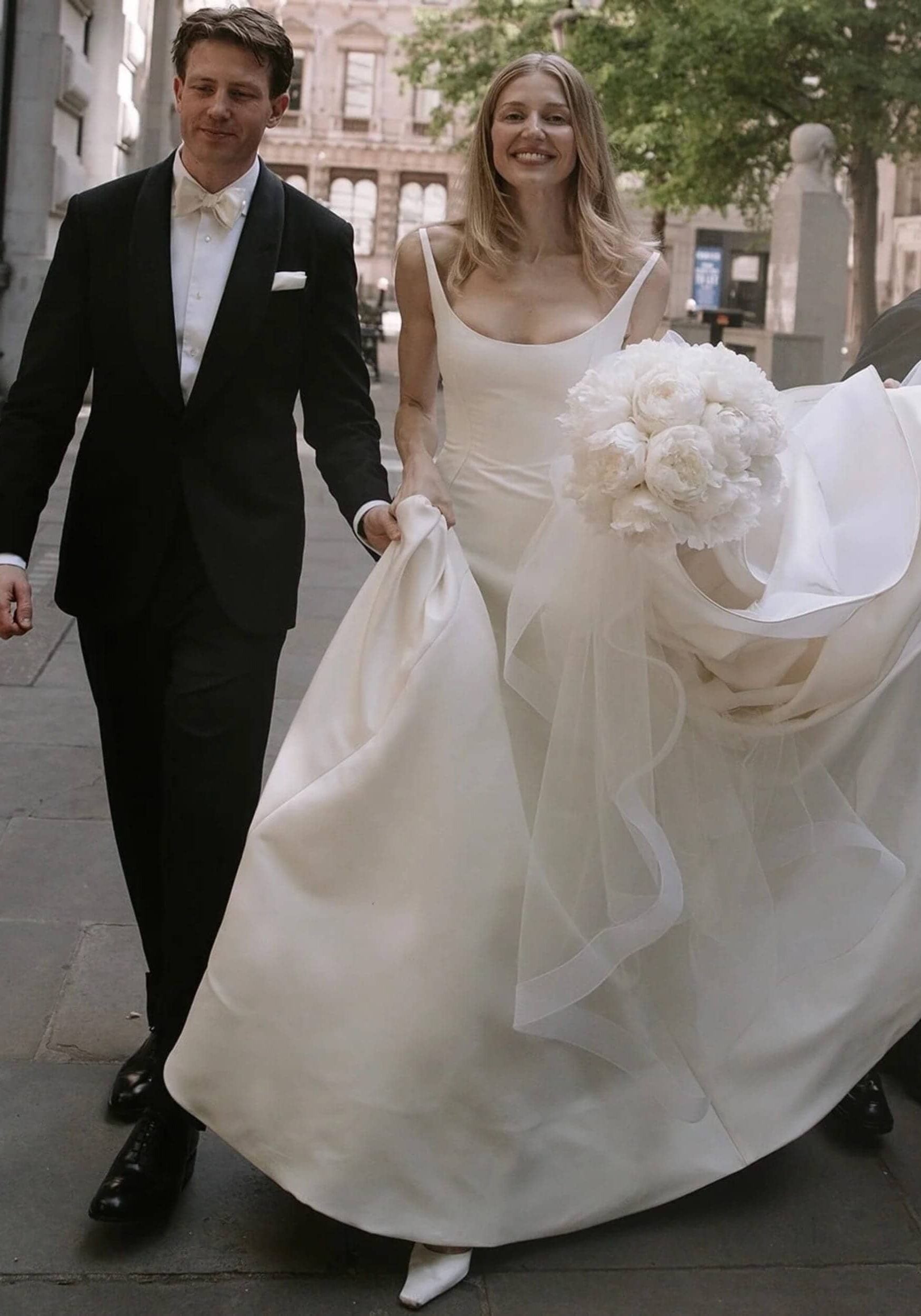 Bride and groom walking outside with wedding bouquet